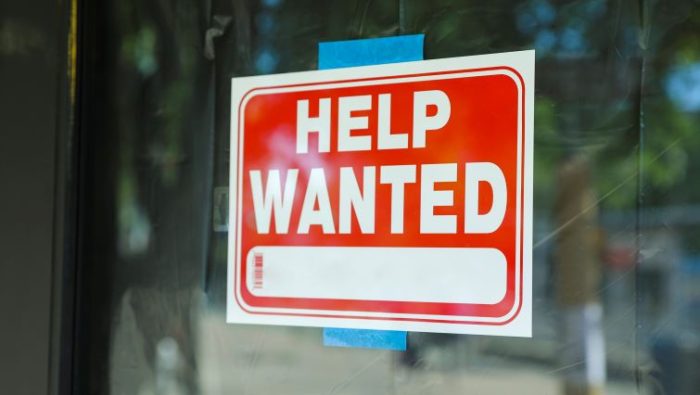 A help wanted sign hanging in a window.