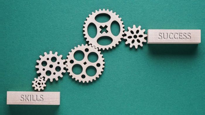 A set of gears creating a path from skills to success.