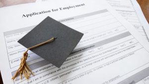 7 Top Entry Level Jobs for 2023 Graduates - A graduation cap on top of a resume.