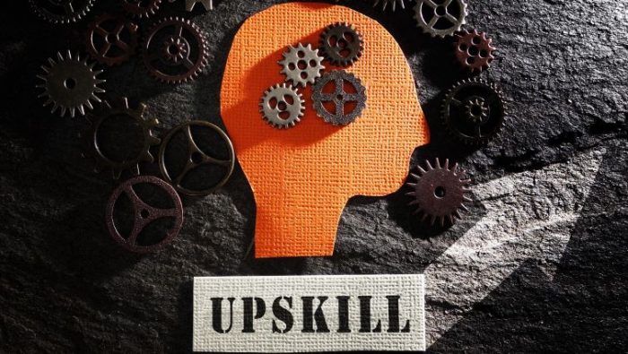 The Upskilling Revolution - An outline of a person heads filled with turning gears in the process of learning, and the work UPSKILLING written underneath.