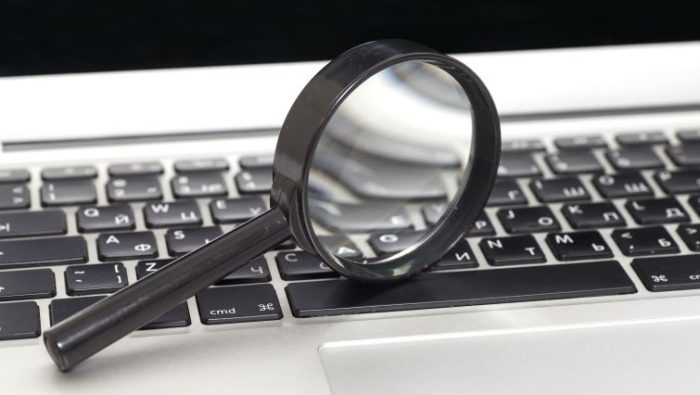 8 Tips For Researching A Company Before Your Job Interview - a magnifying glass over a laptop.
