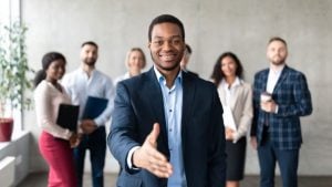 Fostering a Welcoming Environment - HR Strategies for Integrating Immigrant Employees - a group of businesspeople ready to welcome their new colleague to the workplace.
