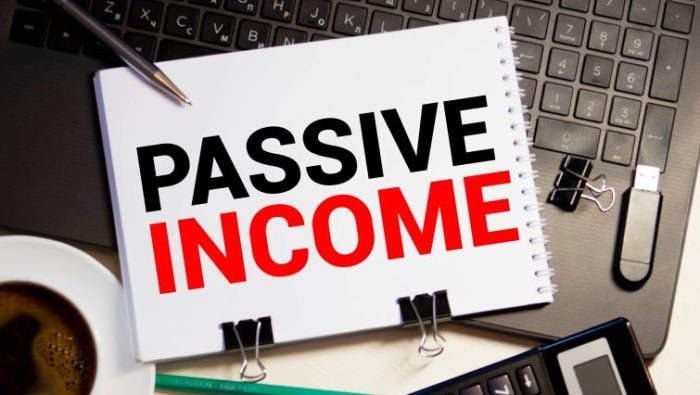 Passive Income Ideas for Freelancers and Remote Workers - a large paper pad with PASSIVE INCOME written on it, sitting on desk in front of a computer.