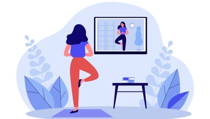 Tips for Employees' Health and Wellness While WFH - a person working from home does yoga while watching a yoga class on her screen.