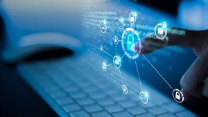 5 Tips For Writing An Effective Cybersecurity Resume - a hand typing on a laptop with logos related to cybersecurity on the screen.