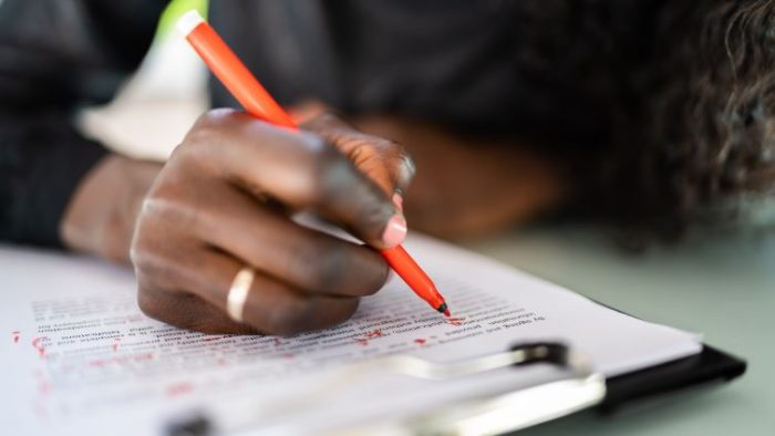 How to Revamp Your Resume in 5 Steps - a person edits their resume with a red pen.