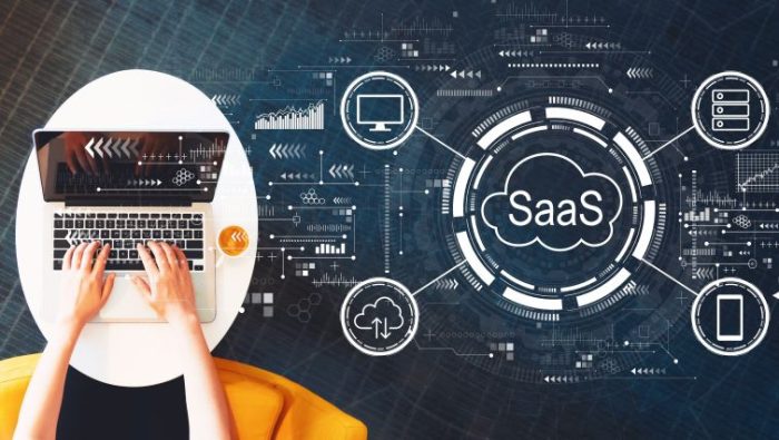 How to Create a Stand-Out SaaS Sales Resume - a person typing on a laptop computer with a giant SaaS logo next to them.