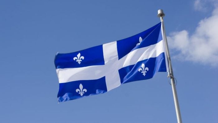 The Minimum Wage in Quebec in 2024 - the flag of Quebec fluttering in the breeze.