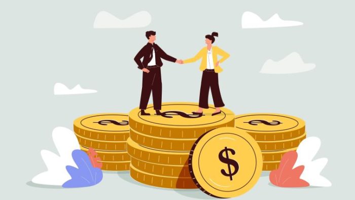 A Guide to Negotiating Salary and Benefits - two business people standing on stacks of coins and shaking hands.